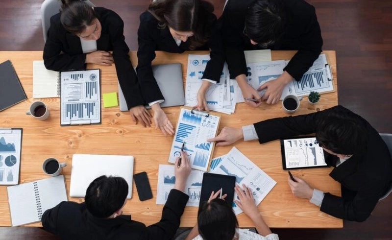 투자 전략을 세우기 위해 테이블에 둘러앉아 토론하는 사람들