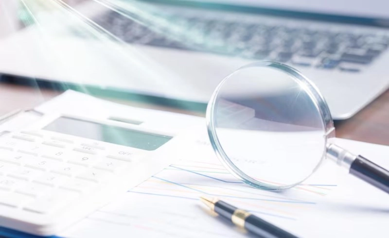 금융 서류를 돋보기로 자세히 살펴보는 모습